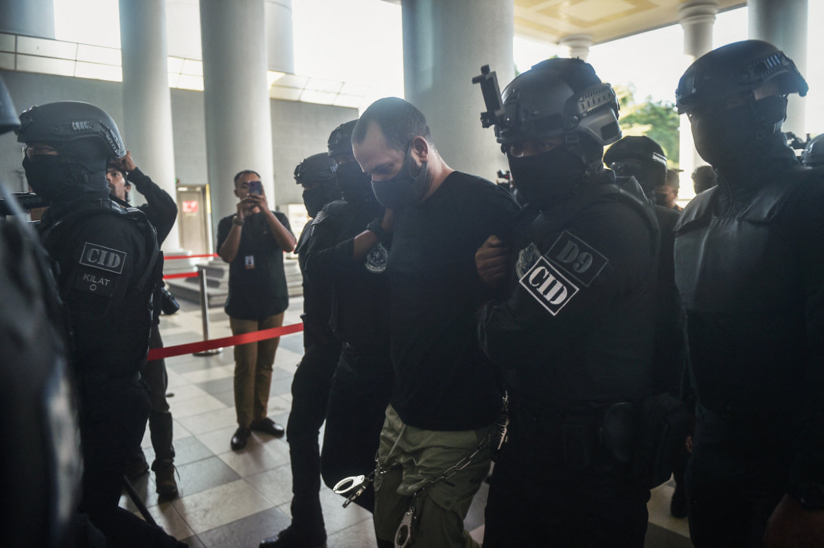 Un Israélien identifié comme Shalom Avitan (C) est escorté par la police malaisienne à son arrivée au tribunal pour faire face à des accusations de possession de six armes de poing et de 200 balles à Kuala Lumpur le 12 avril 2024. (AFP/File)