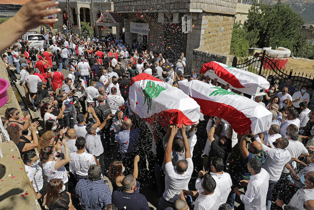 Des parents proches portent les cercueils des pompiers Charbel Hitti, Najib Hitti et Charbel Karam au milieu du cortège funèbre, dans leur ville natale de Qartaba, au nord de la capitale libanaise Beyrouth. (AFP)