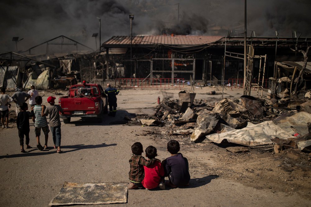 Des enfants assis par terre, dans le camp incendié de Moria sur l'île de Lesbos, après le déclenchement d'un feu majeur, le 9 septembre 2020 (AFP / Fichier Photo)