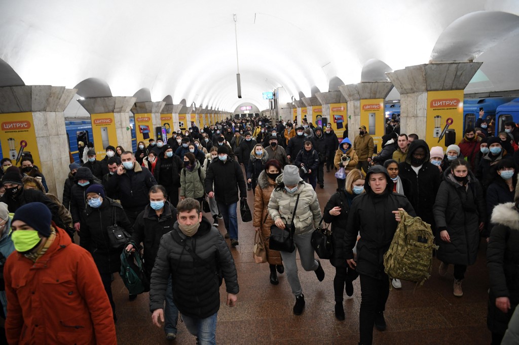 Des gens portant des sacs et des valises, marchent dans une station de métro à Kiev tôt le 24 février 2022. (Photo, AFP)