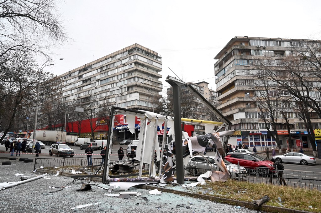 Des personnes à l'extérieur de la zone bouclée autour des restes d'un obus dans une rue de Kiev le 24 février 2022. (Photo, AFP)