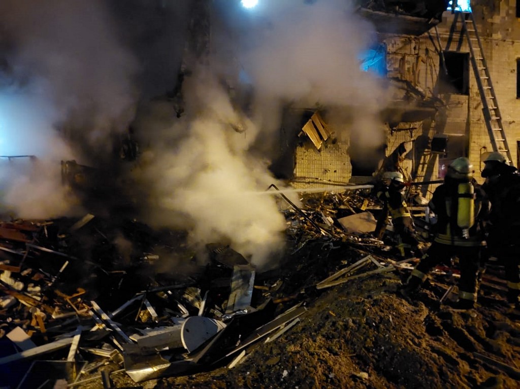 Les pompiers éteignent un incendie dans un immeuble résidentiel endommagé de la rue Koshytsa, une banlieue de la capitale ukrainienne Kiev, tôt le 25 février 2022. Les forces d'invasion russes se sont enfoncées profondément en Ukraine alors que des batailles meurtrières atteignaient la périphérie de Kiev, avec des explosions entendues dans la capitale tôt vendredi. (Photo, AFP)