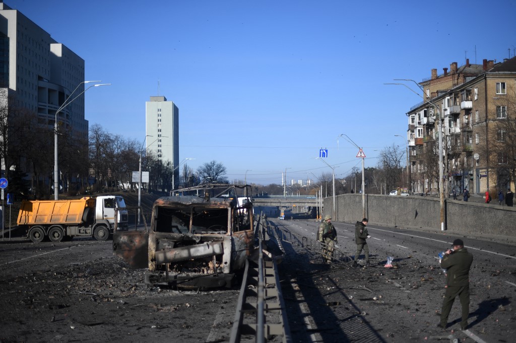 Des soldats ukrainiens se tiennent devant un véhicule de l'armée ukrainienne incendié du côté ouest de la capitale ukrainienne de Kiev, le 26 février 2022. (Photo, AFP)