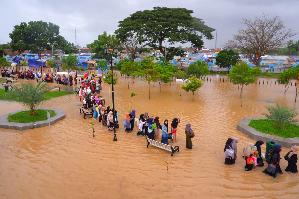Les gens pataugent dans les eaux de crue alors qu'ils évacuent après les inondations à Serang, dans la province de Banten, le 1er mars 2022.