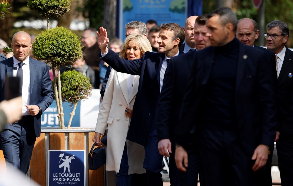 Le président français Emmanuel Macron et son épouse Brigitte Macron s'entretiennent avec les spectateurs avant de voter pour le premier tour de l'élection présidentielle française dans un bureau de vote du Touquet, dans le nord de la France, le 10 avril 2022 (Photo, AFP). 