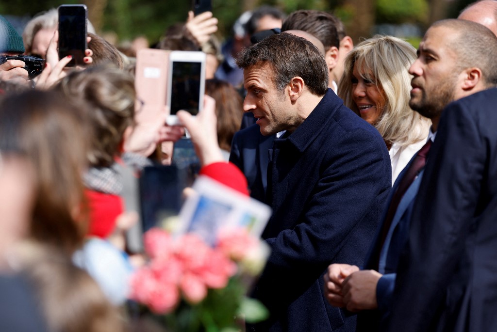 Le président français Emmanuel Macron et son épouse Brigitte Macron s'entretiennent avec les spectateurs avant de voter pour le premier tour de l'élection présidentielle française dans un bureau de vote du Touquet, dans le nord de la France, le 10 avril 2022 (Photo, AFP). 