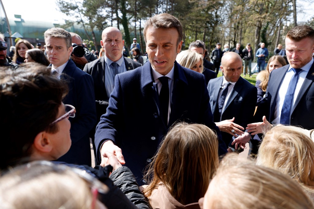 Le président français et candidat présidentiel LREM Emmanuel Macron serre la main d'un enfant alors qu'il parle avec des spectateurs après avoir voté pour le premier tour de l'élection présidentielle française dans un bureau de vote du Touquet, dans le nord de la France, le 10 avril 2022 (Photo, AFP). 