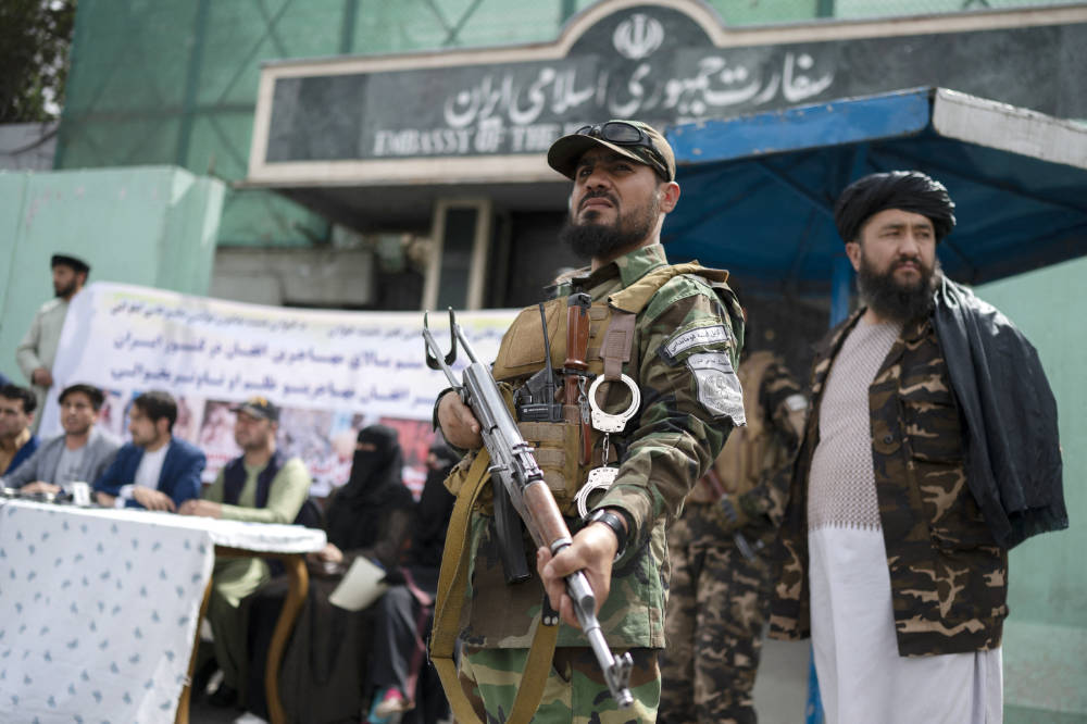 Des combattants talibans montent la garde alors que des manifestants afghans se mobilisent contre les rapports publiés sur le harcèlement des réfugiés afghans en Iran, devant l'ambassade d'Iran à Kaboul, le 11 avril 2022. (AFP)