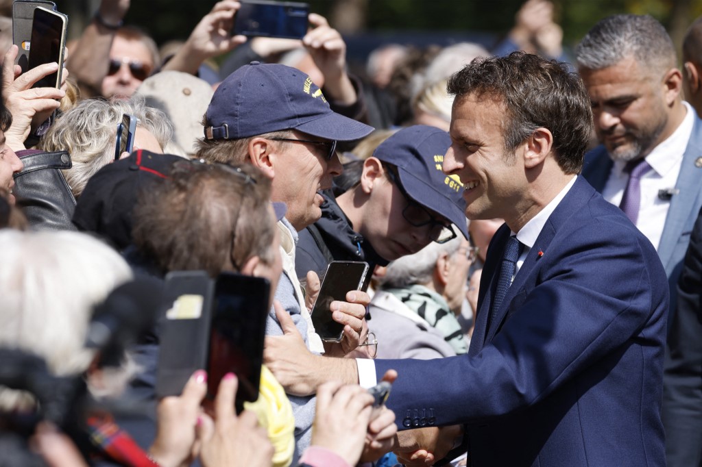 Le président français Emmanuel Macron serre la main des gens alors qu'il arrive pour voter (Photo, AFP). 