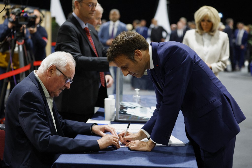 Le président français Emmanuel Macron, candidat à sa réélection, signe le registre électoral après avoir voté pour le second tour de l'élection présidentielle française dans un bureau de vote du Touquet, dans le nord de la France, le 24 avril 2022 (Photo, AFP). 
