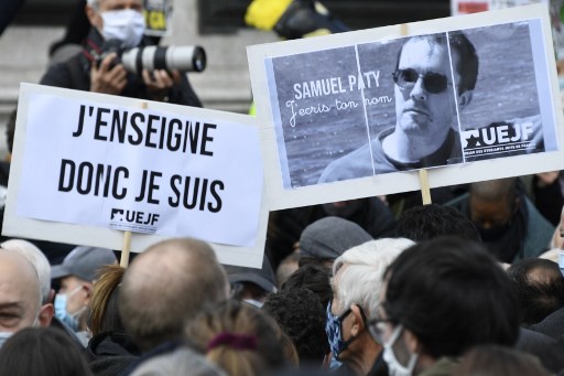 Les gens tiennent une pancarte indiquant «J'enseigne donc je suis» et un portrait du professeur d'histoire Samuel Paty lors d'un rassemblement à la place de la République le 18 octobre 2020, deux jours après avoir été décapité par un agresseur abattu par les policiers (Photo, AFP)