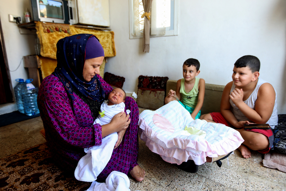 La réfugiée syrienne Rima Jassem tenant sa fille âgée d’à peine quelques semaines, assise avec ses garçons dans une petite pièce sur le toit d'un immeuble surplombant le port ravagé de la capitale libanaise. (AFP/fichier photo)