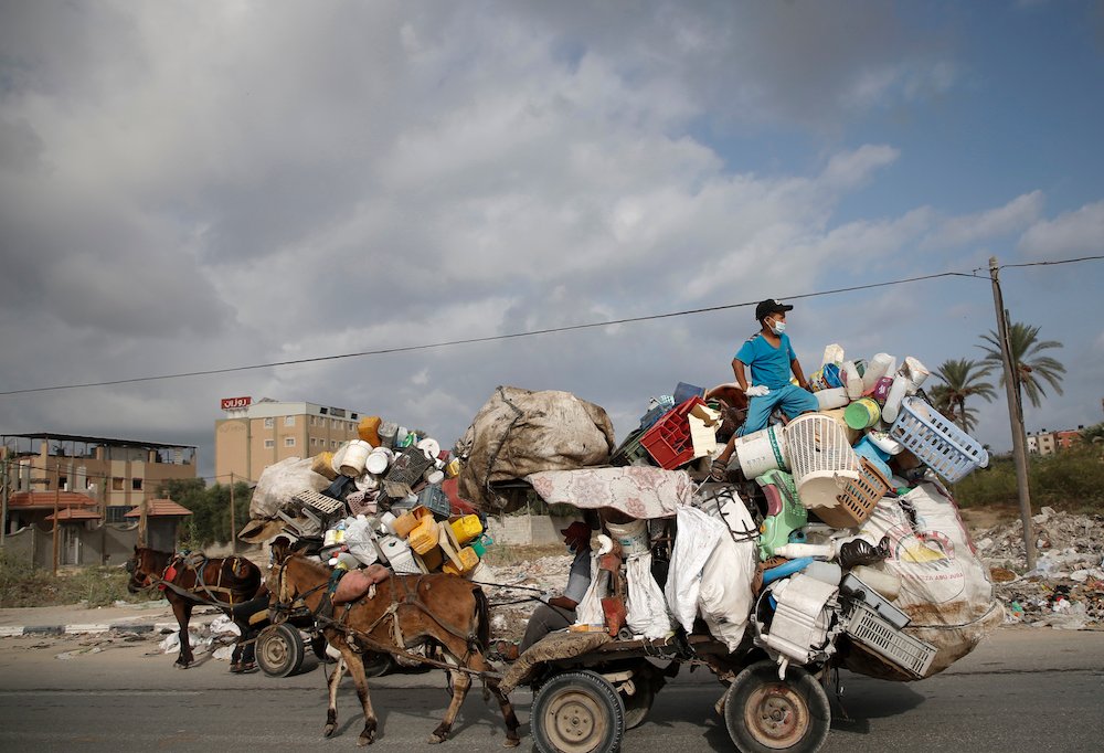 Un Palestinien qui récupère des contenants en plastique sur sa charrette porte un masque de protection, en raison de la COVID-19, à Deir al-Balah, dans le centre de la bande de Gaza, le 1er octobre 2020 (AFP)