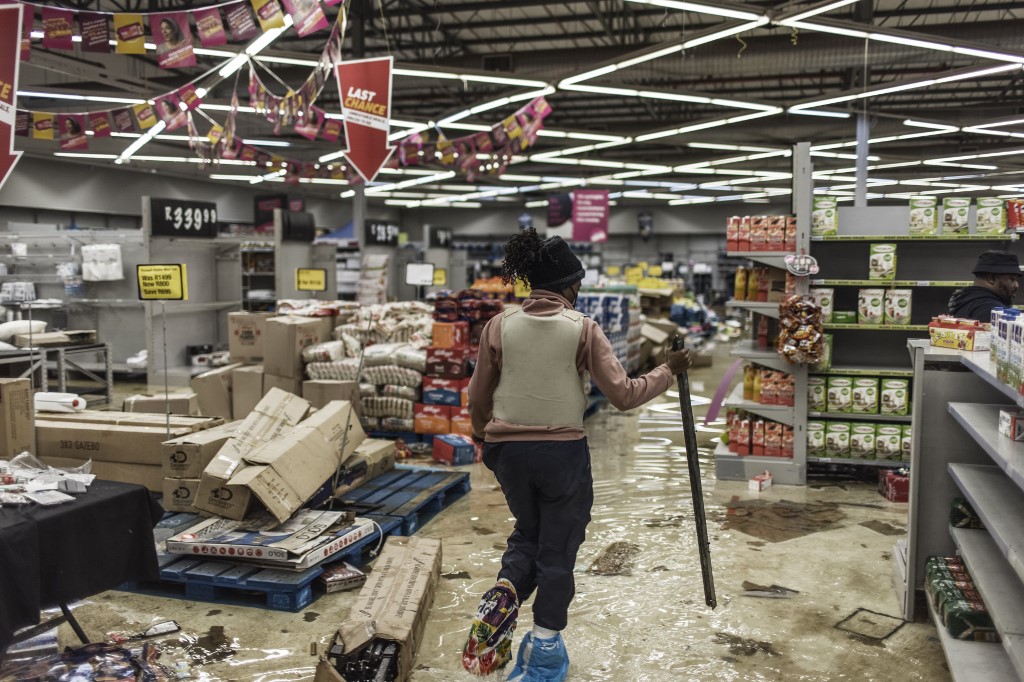 Un policier sud-africain inspecte les dégâts dans un centre commercial pillé à Vosloorus, le 13 juillet 2021.