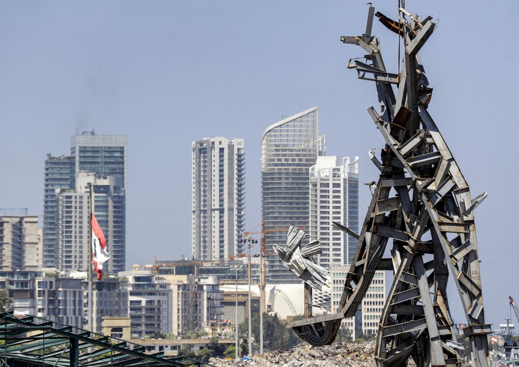 Cette photo prise le 28 juillet 2021 montre une vue d'une sculpture en acier de 25 mètres de haut surnommée "Le geste" par l'artiste libanais Nadim Karam, fabriquée à partir de débris résultant de l'explosion dans le port de la capitale libanaise Beyrouth qui a pris lieu le 4 août 2020, suspendu à une grue sur le site de l'explosion au port près du désormais emblématique silo à grains endommagé