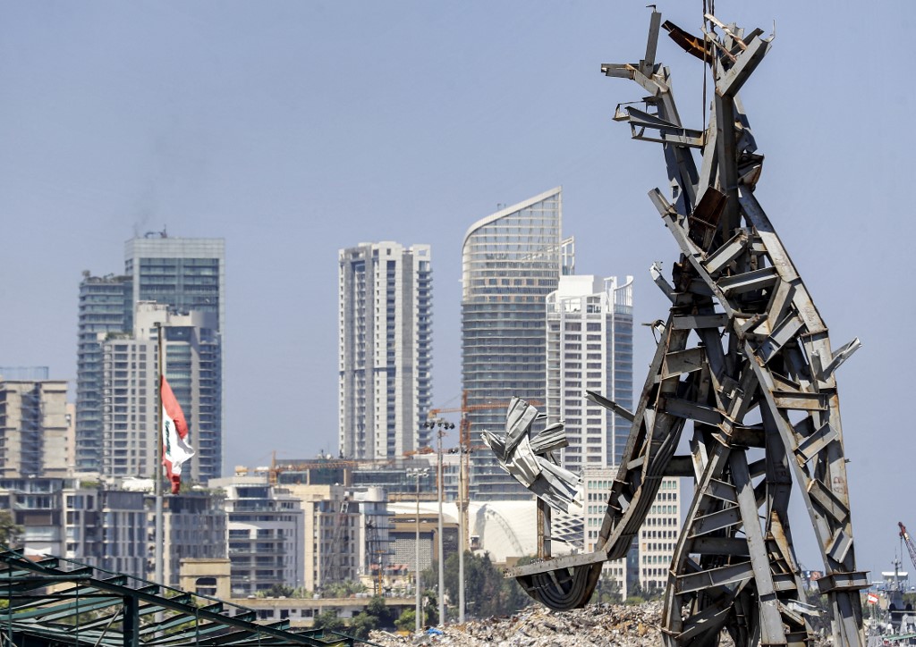 Cette photo prise le 28 juillet 2021 montre une vue d'une sculpture en acier de 25 mètres de haut surnommée "Le geste" par l'artiste libanais Nadim Karam, fabriquée à partir de débris résultant de l'explosion dans le port de la capitale libanaise Beyrouth qui a pris lieu le 4 août 2020, suspendu à une grue sur le site de l'explosion au port près du désormais emblématique silo à grains endommagé