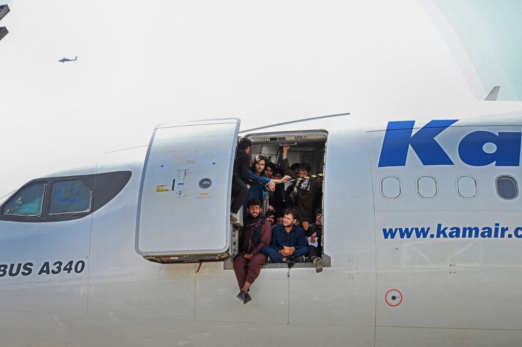 Des Afghans montent dans un avion et s'assoient près de la porte en attendant à l'aéroport de Kaboul à Kaboul le 16 août 2021