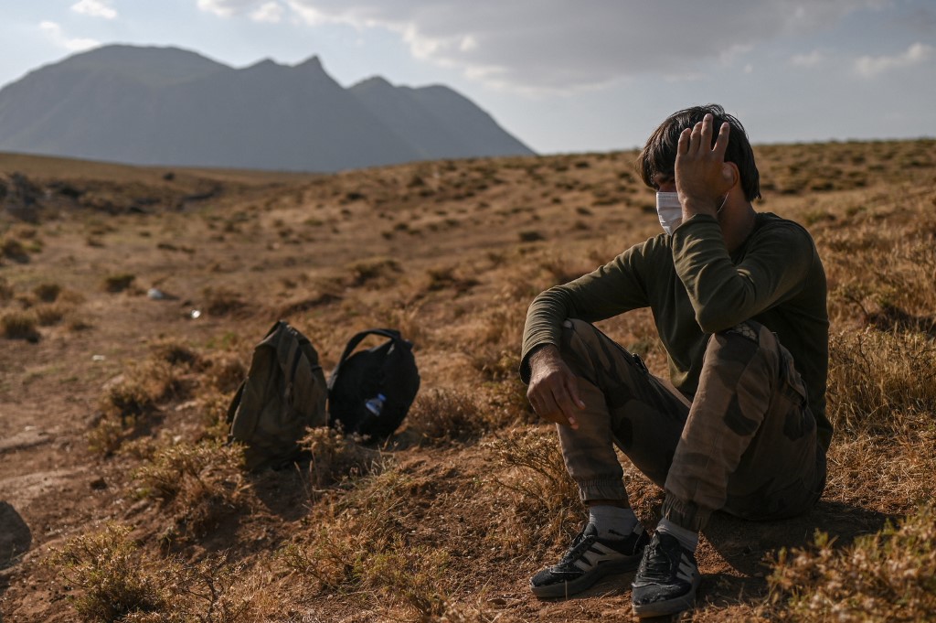 Un migrant afghan se repose en attendant d'être transporté par des passeurs après avoir traversé la frontière irano-turque le 15 août 2021 à Tatvan, sur la rive ouest du lac de Van, dans l'est de la Turquie