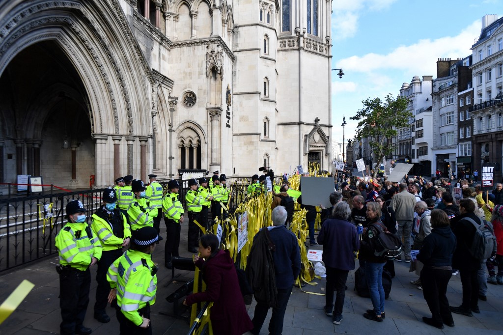 Des responsables de la police montent la garde alors que des manifestants en faveur du fondateur de Wikileaks, Julian Assange, tiennent des pancartes devant la Cour royale de justice de Londres lors d'une audience d'appel du gouvernement américain contre le refus du Royaume-Uni de l'extrader, le 27 octobre 2021. (Photo, AFP)