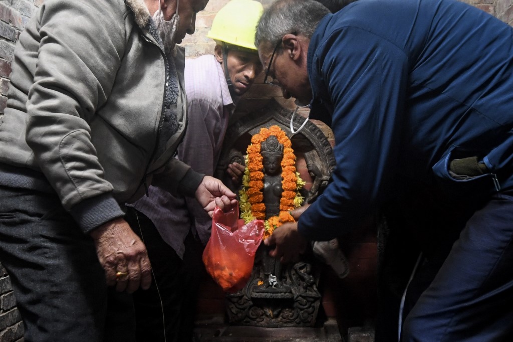 Les fidèles réinstallent une sculpture centenaire d'un dieu hindou dans son temple de Patan (Lalitpur) à la périphérie de Katmandou le 4 décembre 2021, près de 40 ans après son vol et son apparition aux États-Unis et son retour au Népal du musée d'art de Dallas.