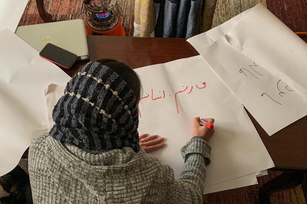 Une femme afghane écrit des pancartes avant une marche de protestation pour les droits des femmes, à Kaboul. La photo est prise le 15 janvier 2022 ( AFP )