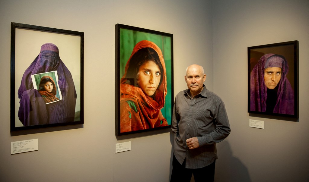 Le photographe américain Steve McCurry pose à côté de ses photos de la "Afghan Girl" nommée Sharbat Gula lors de l'ouverture de l'exposition "Overwhelmed by Life" de son travail au Museum for Art and Trade de Hambourg, dans le nord de l'Allemagne, le 27 juin 2013
