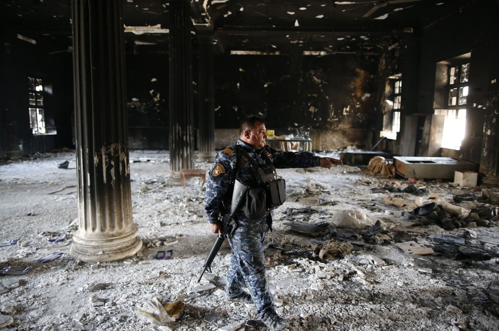 Un membre des forces irakiennes inspecte les dégâts à l'intérieur du musée détruit de Mossoul le 2 avril 2017 après l'avoir repris aux combattants du groupe État islamique (EI). AHMAD GHARABLI / AFP