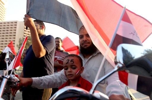Un Egyptien arrive avec son fils, arborant les couleurs du drapeau de son pays et du numéro 25, faisant référence au 25 janvier 2011 le début de la révolution qui a évincé le dirigeant égyptien Hosni Moubarak, sur la place Tahrir du Caire, le 24 juin 2012 (Photo, AFP)
