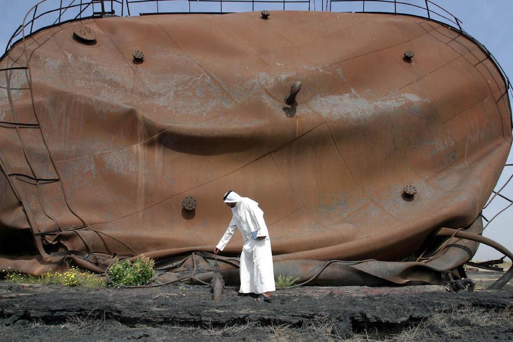 Barak al-Hindi, journaliste koweïtien, se tient sur un sol calciné, le 12 mars 2003, devant un réservoir de pétrole endommagé, lors de sa visite dans le centre pétrolier d'al-Ahmadi, aux abords de la ville de Koweït, détruit par les troupes irakiennes lorsqu'elles ont fui le Koweït au terme de la guerre du Golfe en 1991. (AFP/File Photo)