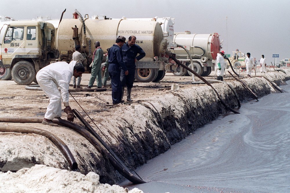 Des agents de nettoyage pompent le pétrole d'un réservoir artificiel dans des camions stationnés sur place, le 18 mars 1991; le pétrole relâché par l'armée irakienne pendant la guerre du Golfe continue de flotter vers le sud du Golfe Arabique. (AFP/File Photo)