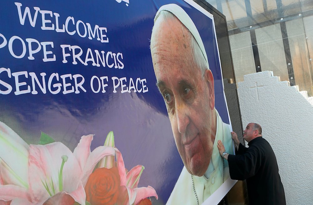 Le Père Nadhir Dako place un poster de bienvenue pour le Pape François à l'église chaldéenne Saint-Joseph en préparation de la visite du Pape, à Bagdad. (AP)