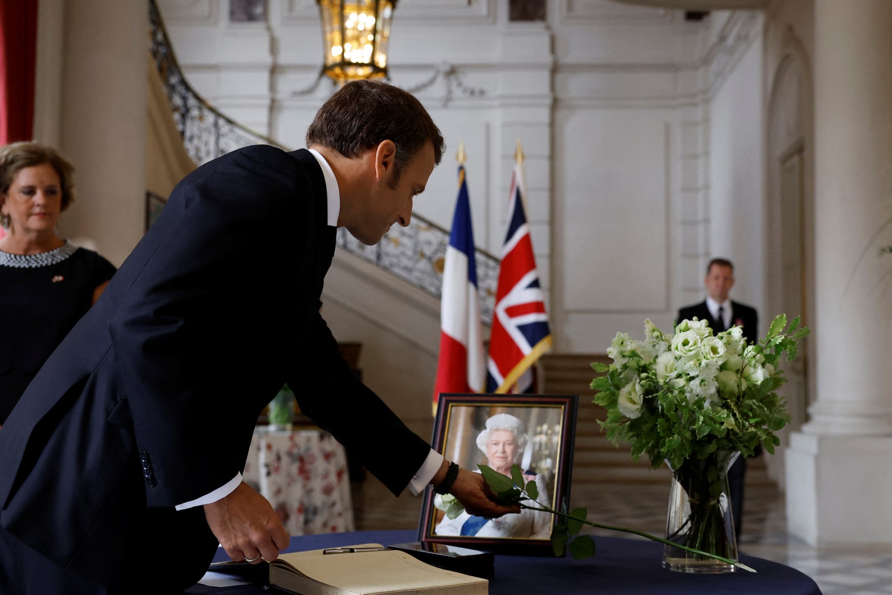 Le président français Emmanuel Macron place une rose blanche à côté d'un portrait de la reine Elizabeth II, après avoir signé le livre de condoléances à l'ambassade britannique à Paris, le 9 septembre 2022. (Photo : Christian Hartmann / Pool / AFP)