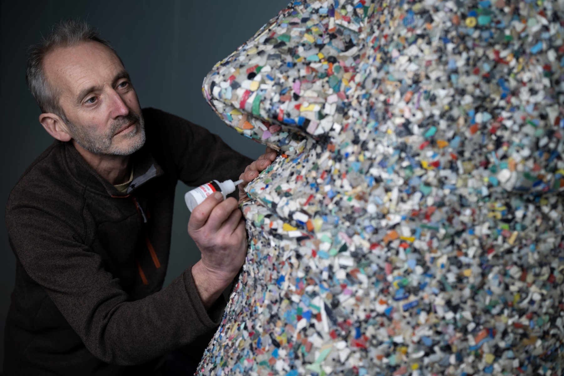 L'artiste et militant écologiste Rob Arnold, travaille sur une sculpture intitulée "A Lesson of history" qu'il a créée en 2017, inspirée des têtes Moai de l'île de Pâques, entièrement réalisée à partir d'aiguilles et autres micro-plastiques ramassés sur la plage, le 27 février 2023, au National Maritime Museum Cornwall, en Cornouailles, dans le sud-ouest de l'Angleterre. (Photo par Ben Stansall / AFP)