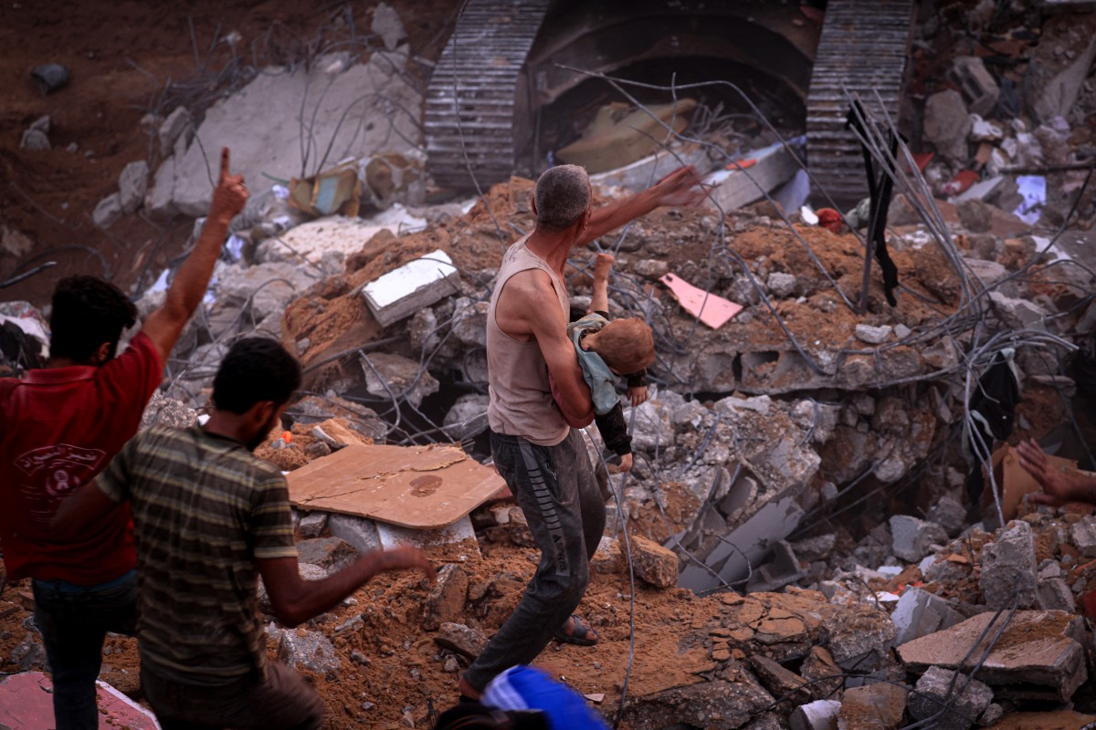 Un Palestinien porte le corps d'un enfant après avoir été déterré des décombres d'un bâtiment du camp de réfugiés de Nuseirat, dans le centre de la bande de Gaza, le 31 octobre 2023, au milieu des bombardements israéliens incessants (Photo de MAHMOUD HAMS / AFP).