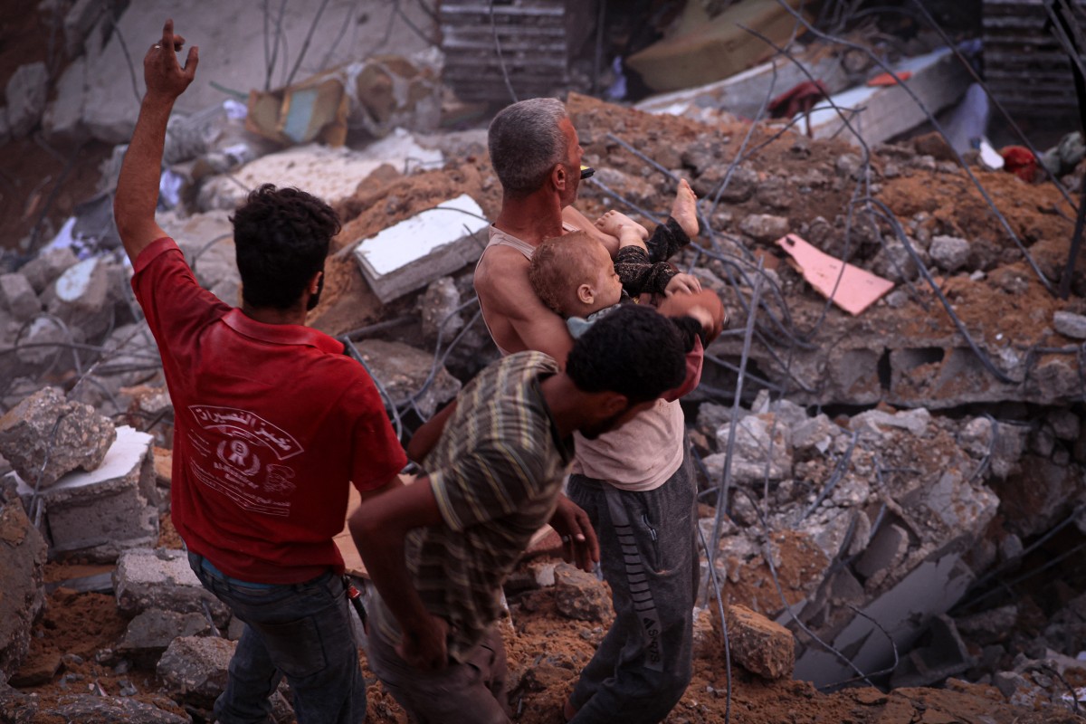 Un Palestinien porte le corps d'un enfant après avoir été déterré des décombres d'un bâtiment du camp de réfugiés de Nuseirat, dans le centre de la bande de Gaza, le 31 octobre 2023 (Photo de MAHMOUD HAMS / AFP).