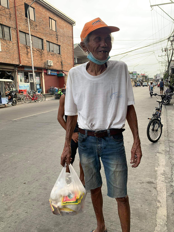 Un homme âgé sourit après avoir obtenu des produits alimentaires à la banque alimentaire du gouverneur Pascual à Malabon. (Photo de la page Facebook de Nine Louise Tesorero) 