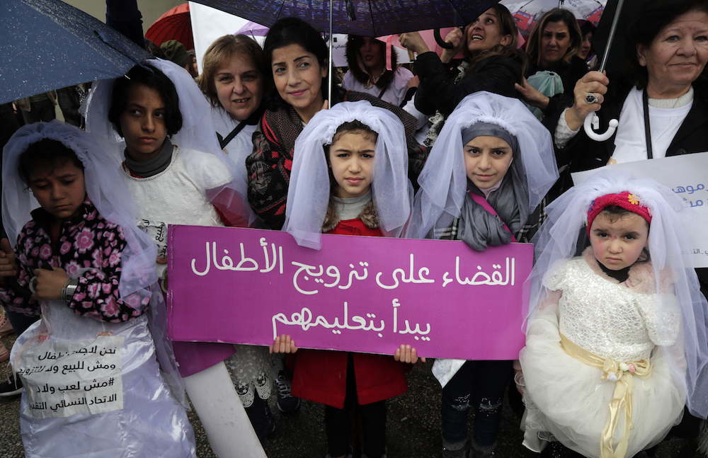 Des jeunes filles libanaises déguisées en mariées brandissent une pancarte lors d’une marche contre le mariage avant l'âge de 18 ans, dans la capitale Beyrouth, le 2 mars 2019. (AFP/ANWAR AMRO/File Photo)
