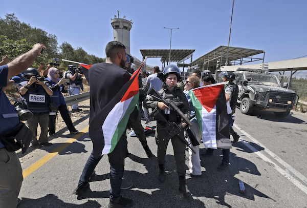 Des activistes palestiniens et autres brandissent des drapeaux nationaux face aux forces de sécurité israéliennes, lors d'une manifestation contre les colonies juives. (AFP)
