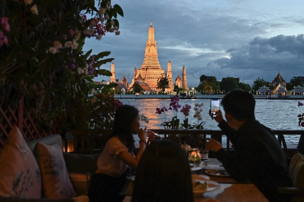 Des touristes profitent d'une vue du temple bouddhiste Wat Arun le long de la rivière Chaophraya. (AFP)