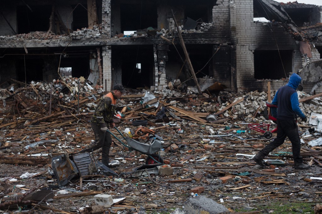Des résidents locaux enlèvent les décombres d'une rue détruite par des tirs d'obus, le 9 avril 2022 à Novoselivka, dans la banlieue de Tchernihiv, en Ukraine.
