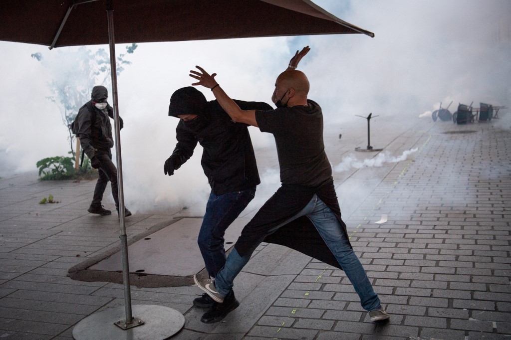 Un propriétaire de bar se bat avec un manifestant lors d'une deuxième manifestation pour marquer le deuxième anniversaire de la mort de Steve Maia Canico décédé en 2019 (AFP)