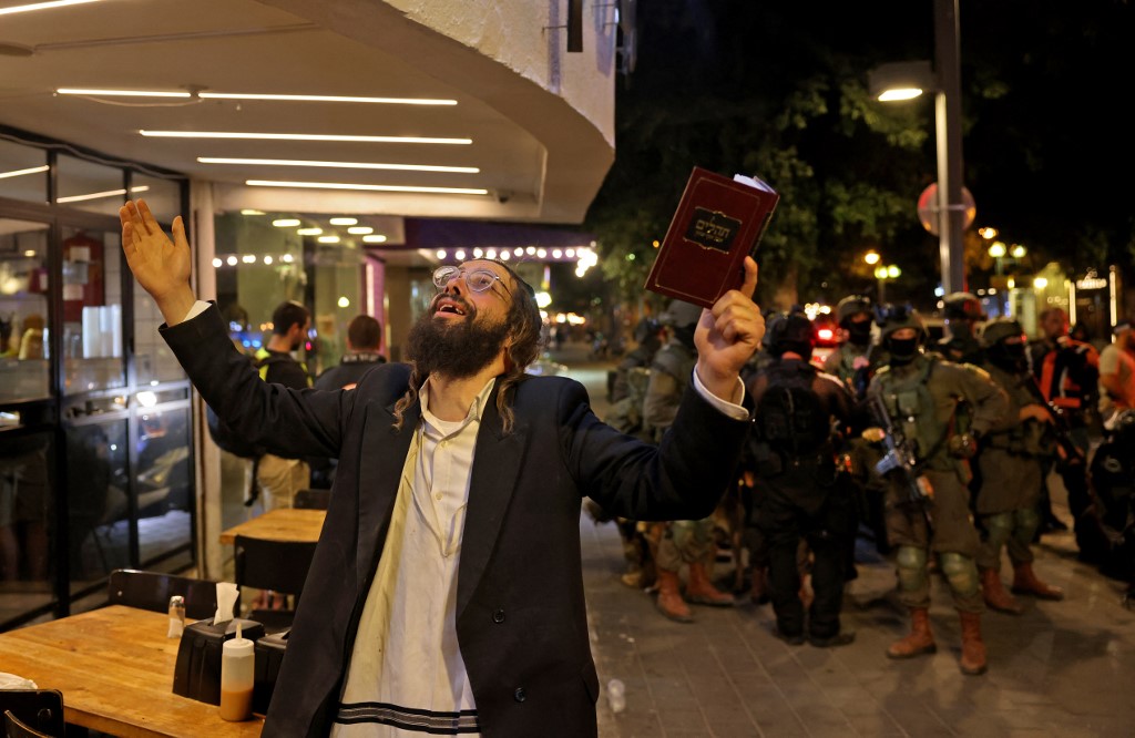 Un Juif ultra-orthodoxe réagit en tenant un volume des Psaumes tandis que les forces de sécurité se rassemblent sur les lieux d'une fusillade dans la rue Dizengoff, au centre de Tel Aviv, le 7 avril 2022