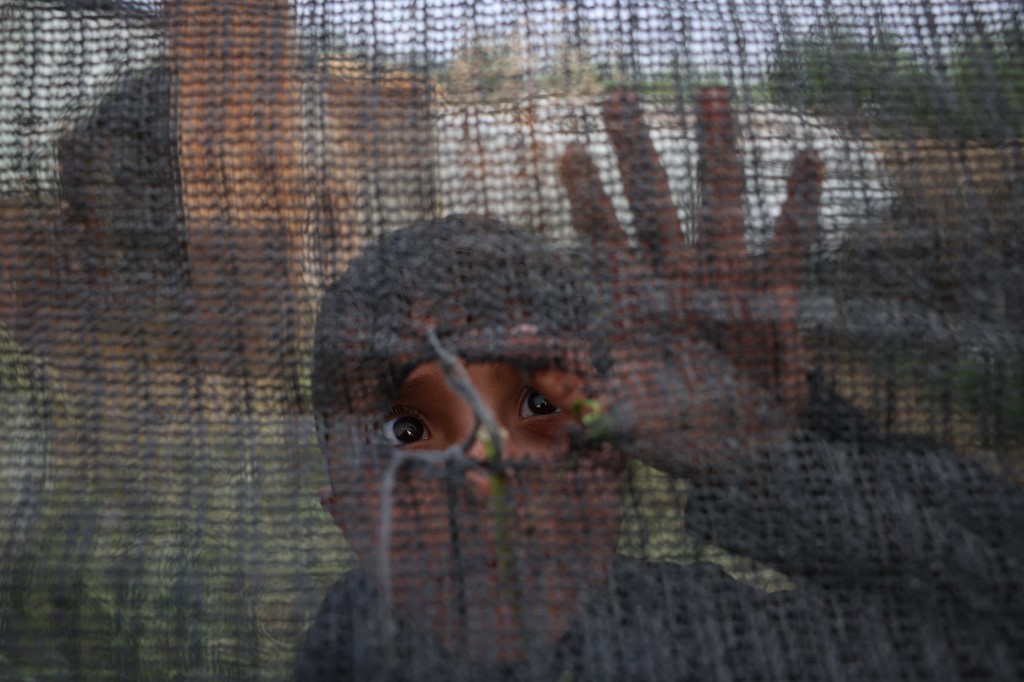 Un garçon palestinien regarde par un trou dans une clôture près de la frontière entre Gaza et Israël à al-Bureij, le 7 avril 2022