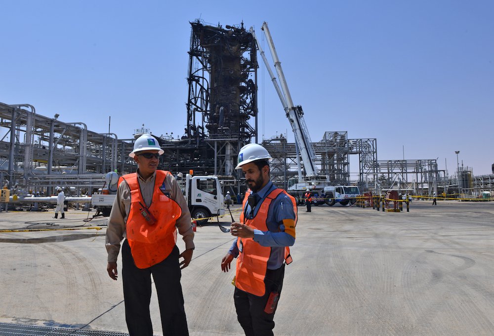 Le 20 septembre 2019, des employés de la compagnie pétrolière Aramco se tiennent près d'une installation gravement endommagée, dans une raffinerie de pétrole de Khurais, en Arabie saoudite (AFP / Fichier Photo)