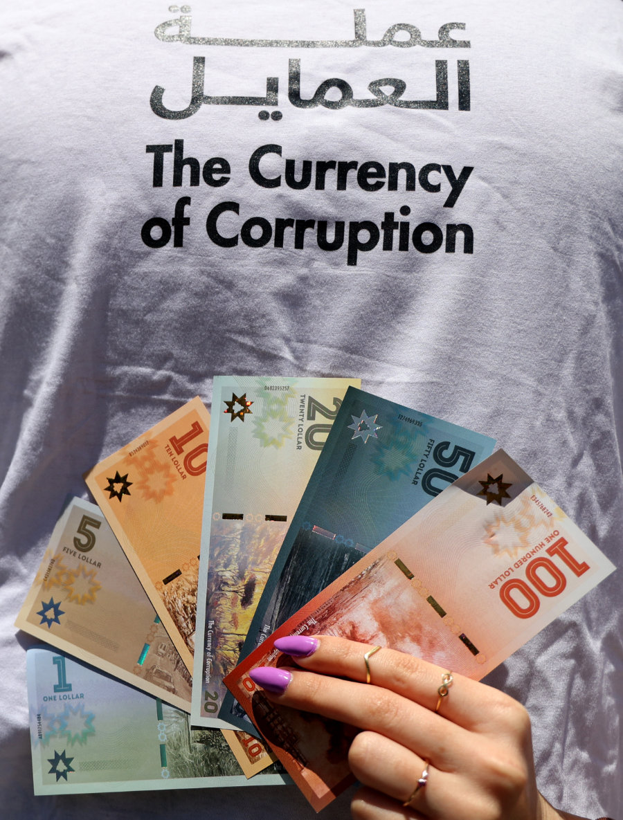Un militant libanais exhibe de faux billets de banque appelés «lollars», devant un faux guichet automatique, pour dénoncer le haut niveau de corruption qui règne dans le pays. (AFP)