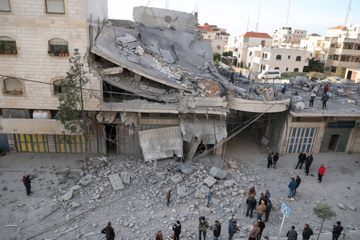 Des Palestiniens se rassemblent près des décombres d’une maison familiale démolie par l’armée israélienne lors d’un raid dans la ville d’Hébron, en Cisjordanie occupée, le 21 janvier 2024. (AFP)