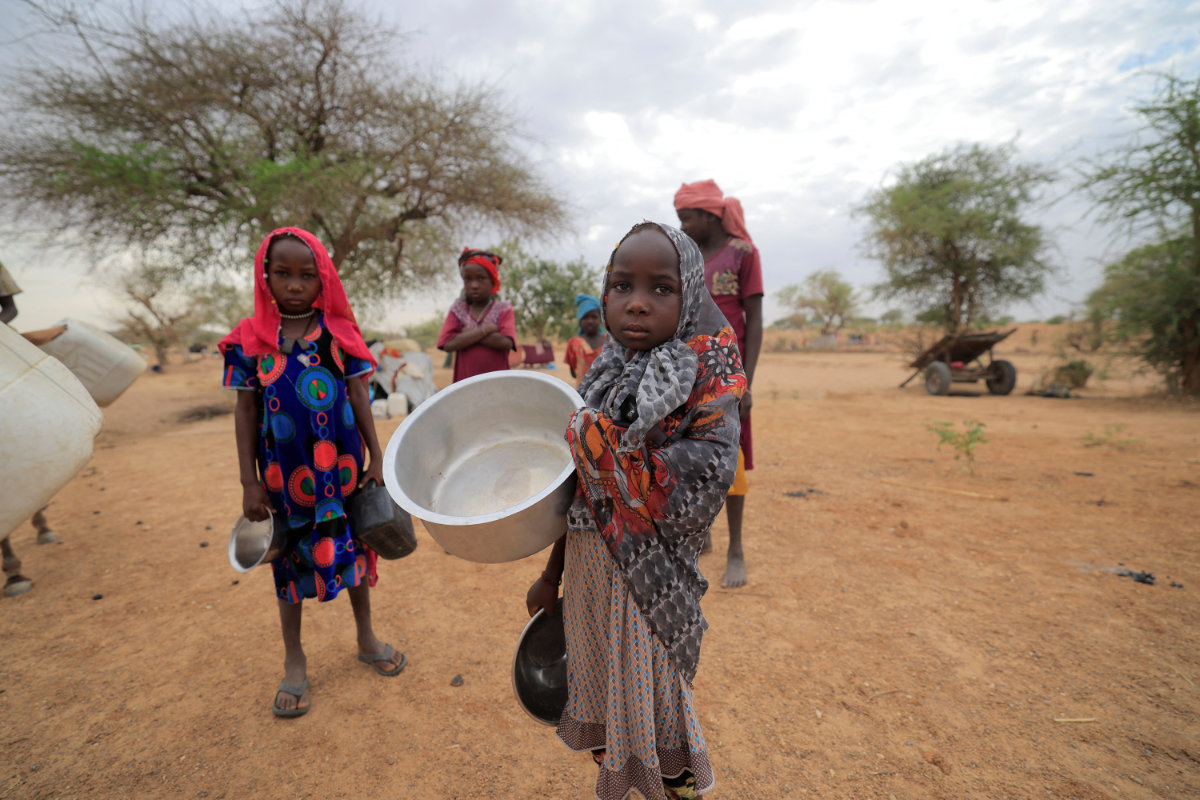 Des enfants soudanais qui ont fui le conflit dans la région du Darfour transportent des pots en route vers un point d'eau à proximité de la frontière entre le Soudan et le Tchad le 12 mai 2023. (REUTERS)