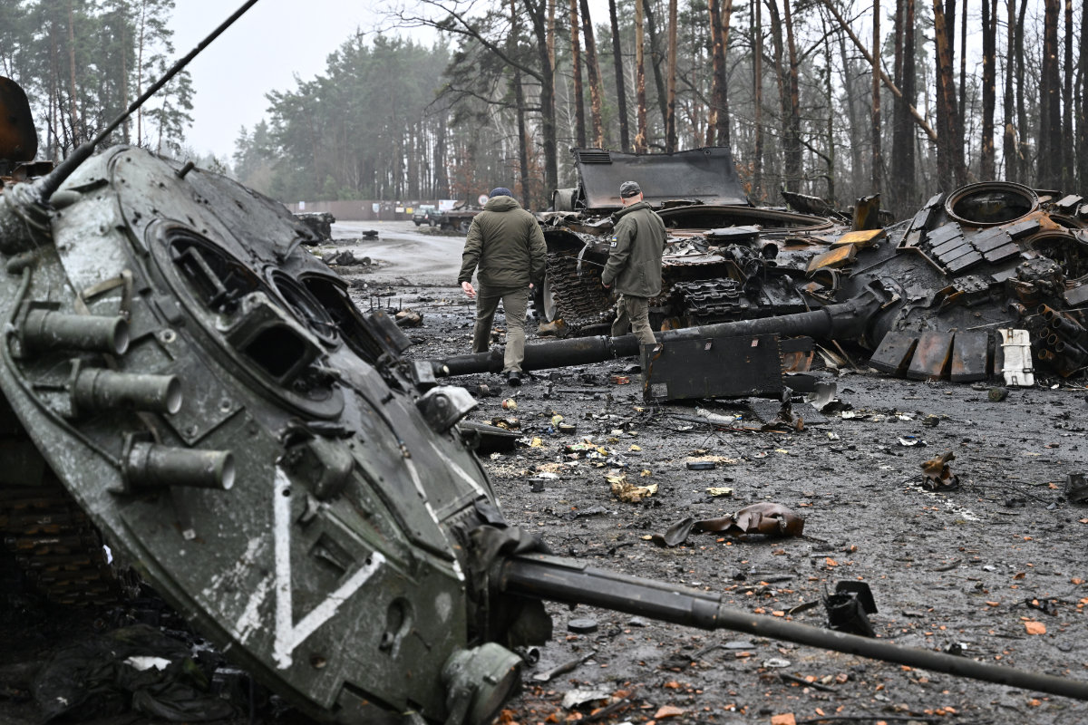 Des militaires ukrainiens marchent à côté de chars et de véhicules blindés de transport de troupes russes détruits dans le village de Dmytrivka, à l'ouest de Kiev, le 2 avril 2022. Les militants de Daech semblent avoir profité du fait que la Russie est distraite par sa guerre désastreuse contre l'Ukraine. (AFP/File)