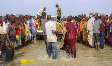 Des hommes portent un corps hors de l'eau sous le regard de badauds à Ngaski, au Nigeria, le 27 mai 2021 après qu'un bateau surchargé a coulé dans le fleuve Niger le 26 mai 2021. (AFP)