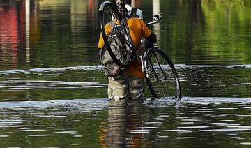 Un habitant porte son vélo alors qu'il marche dans les eaux de crue après de fortes pluies de mousson à Kelaniya, à la périphérie de Colombo, le 6 juin 2021 (Photo, AFP)